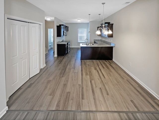 kitchen with sink, range with electric cooktop, dark hardwood / wood-style flooring, decorative light fixtures, and a notable chandelier