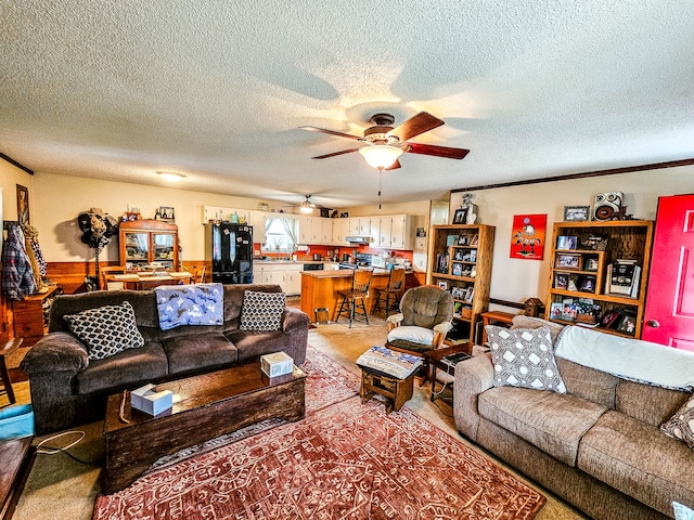 living room featuring a textured ceiling, carpet flooring, ceiling fan, and wood walls