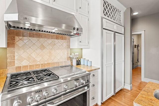 kitchen featuring light wood-type flooring, white cabinetry, backsplash, and high quality appliances