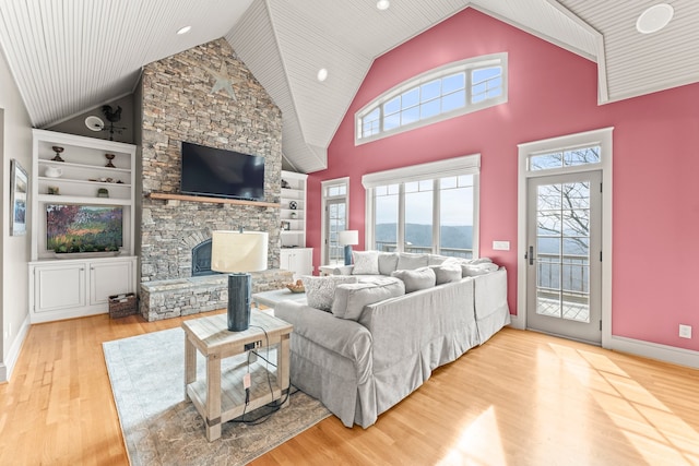 living room featuring built in features, hardwood / wood-style floors, high vaulted ceiling, and a fireplace