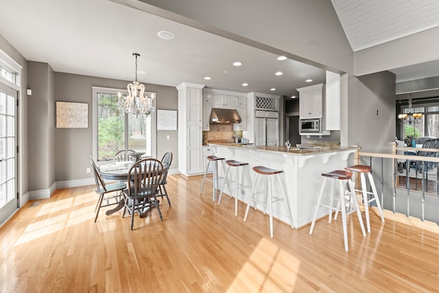 kitchen featuring a wealth of natural light, built in appliances, light wood-type flooring, and white cabinetry