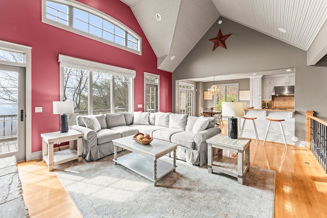 living room with high vaulted ceiling, light hardwood / wood-style flooring, and an inviting chandelier