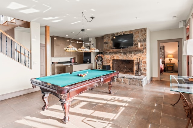 playroom featuring pool table, light tile patterned floors, and a stone fireplace