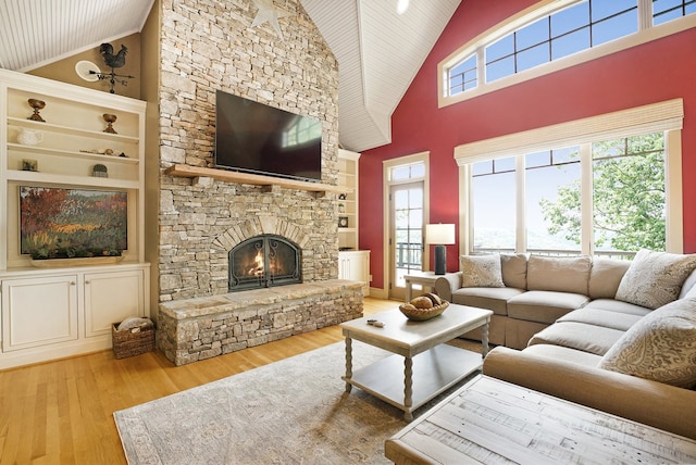 living room featuring high vaulted ceiling, a wealth of natural light, a fireplace, and light hardwood / wood-style floors