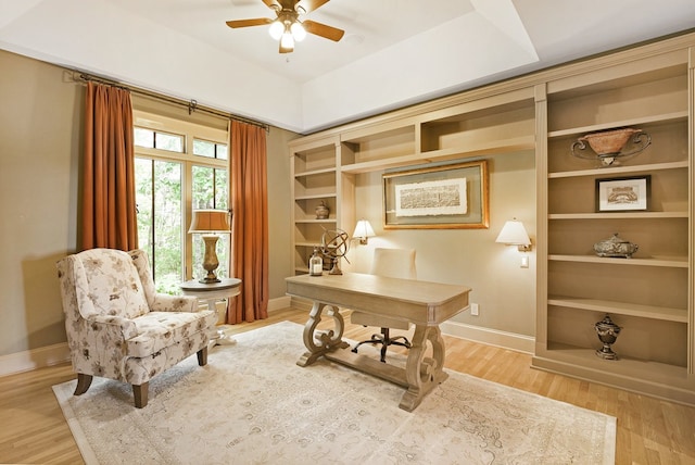 office space featuring light wood-type flooring, built in features, and ceiling fan