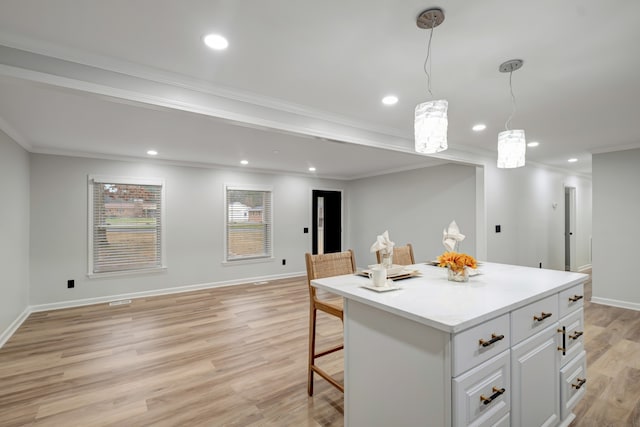 kitchen featuring decorative light fixtures, white cabinetry, light hardwood / wood-style flooring, a center island, and crown molding