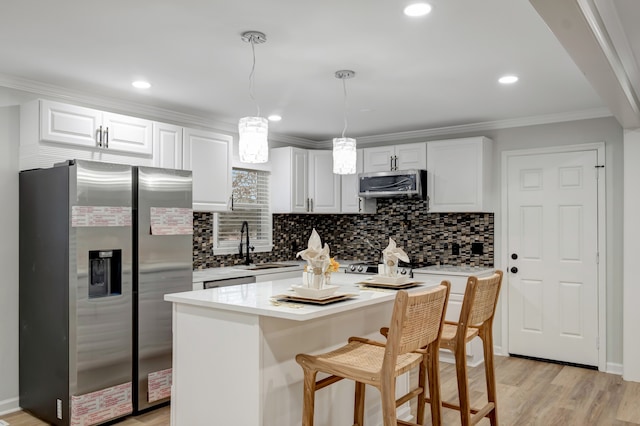 kitchen featuring appliances with stainless steel finishes, tasteful backsplash, light hardwood / wood-style floors, decorative light fixtures, and white cabinets