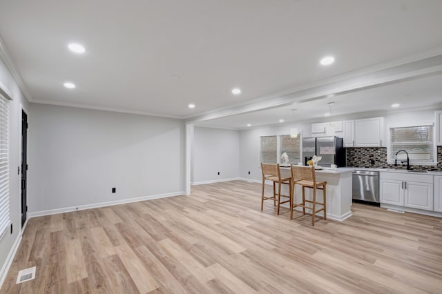 kitchen with appliances with stainless steel finishes, a kitchen island, crown molding, and light hardwood / wood-style flooring