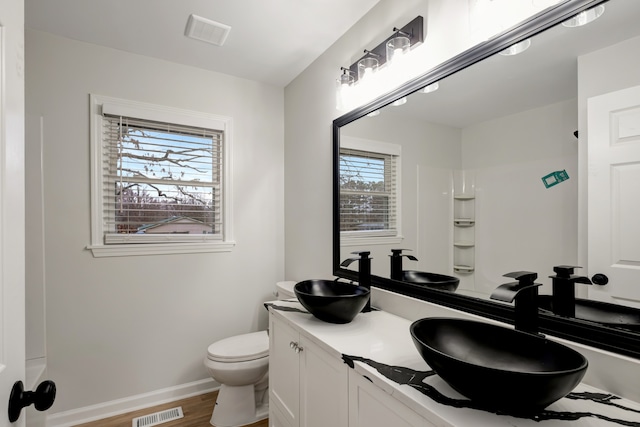 bathroom with hardwood / wood-style floors, toilet, and dual vanity