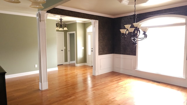 empty room with ornamental molding, a notable chandelier, and wood-type flooring