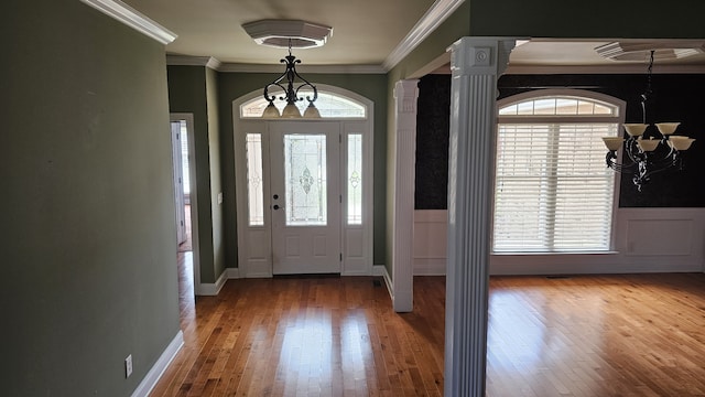 entrance foyer featuring a notable chandelier, plenty of natural light, hardwood / wood-style floors, and ornamental molding