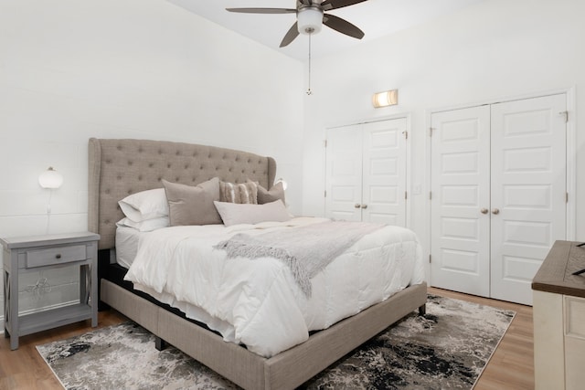 bedroom with two closets, hardwood / wood-style floors, and ceiling fan