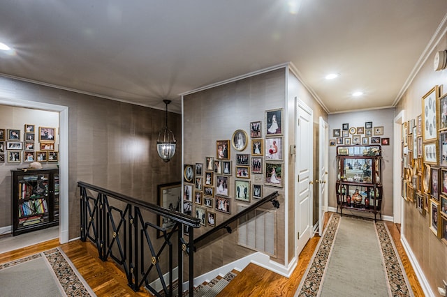 hall featuring an inviting chandelier, crown molding, and dark wood-type flooring