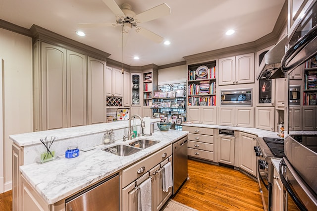 kitchen featuring stainless steel appliances, ceiling fan, hardwood / wood-style floors, a center island with sink, and sink