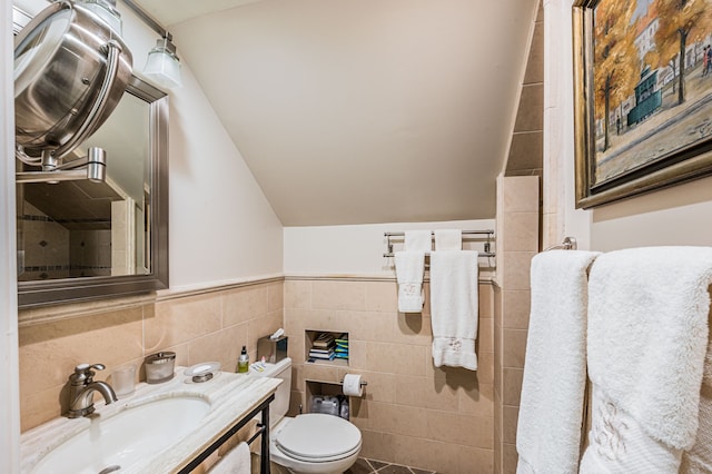 bathroom featuring tasteful backsplash, toilet, vanity, lofted ceiling, and tile walls