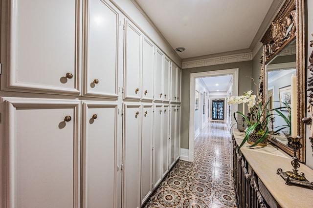 hallway featuring light tile floors and ornamental molding