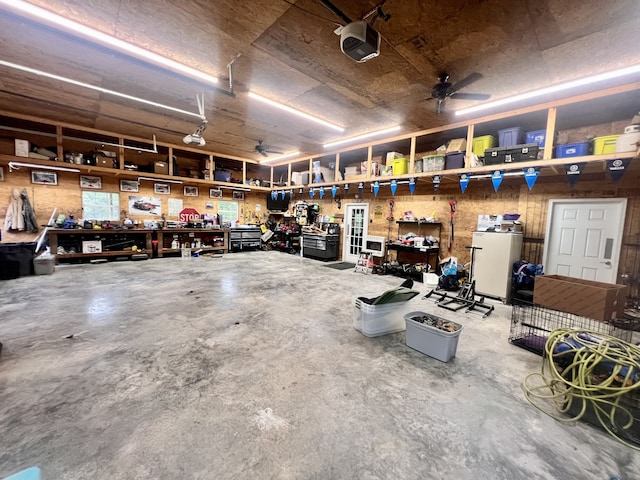 garage with ceiling fan, a garage door opener, a workshop area, and white fridge