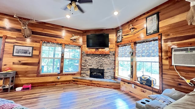 living room with wood-type flooring, a fireplace, plenty of natural light, and ceiling fan