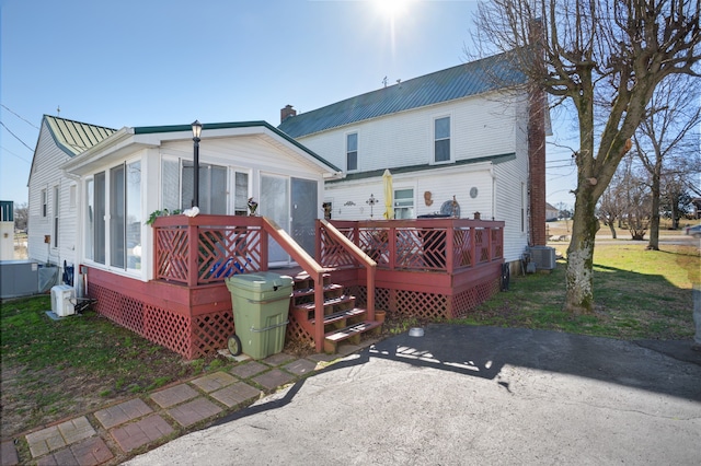 back of property with a wooden deck, a yard, and central AC