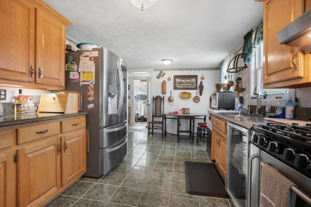 kitchen with dark tile floors, dark stone counters, a textured ceiling, beverage cooler, and wall chimney range hood