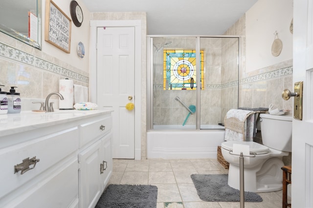 full bathroom with tile floors, large vanity, toilet, and tile walls