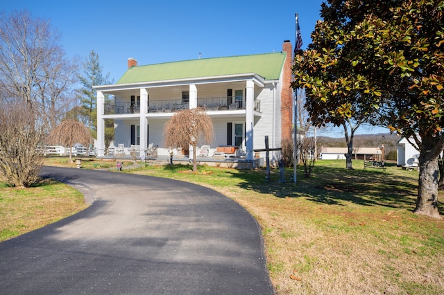 neoclassical / greek revival house featuring a front lawn and a porch