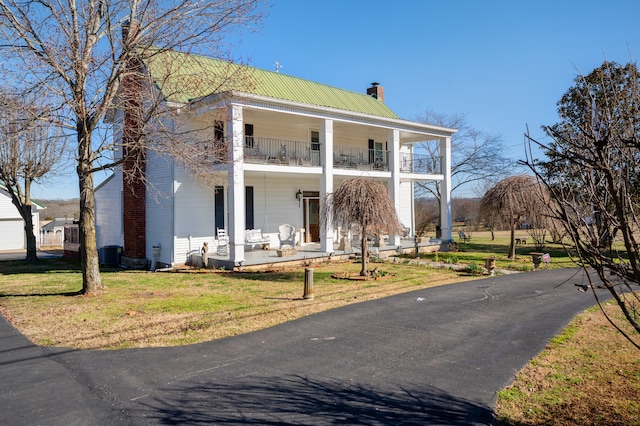 view of front of house featuring a balcony, central air condition unit, covered porch, and a front yard