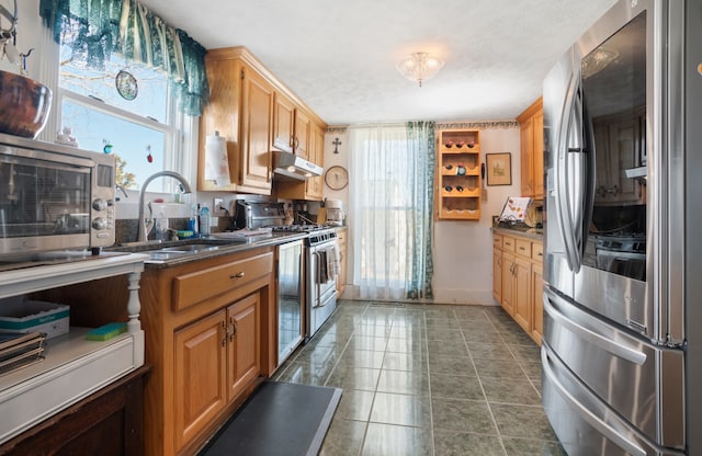 kitchen with stainless steel appliances, dark tile floors, and sink