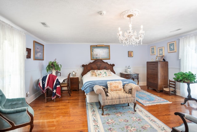 bedroom featuring a chandelier, hardwood / wood-style floors, and crown molding