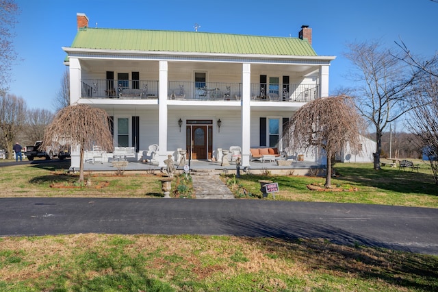 view of front of property with a balcony, a front yard, and a patio area