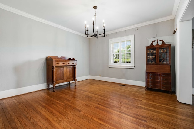 unfurnished room with hardwood / wood-style flooring, crown molding, and a notable chandelier