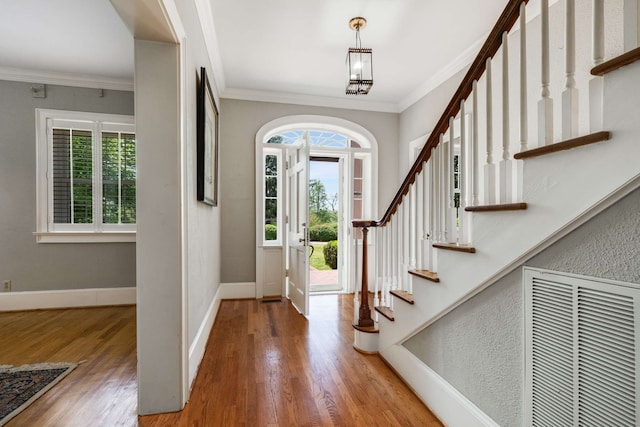 entryway featuring a healthy amount of sunlight, ornamental molding, hardwood / wood-style floors, and a chandelier