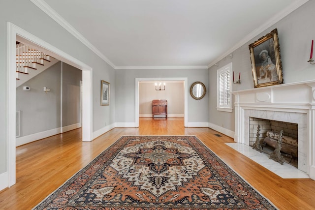 living room with light wood-type flooring, ornamental molding, and a tile fireplace