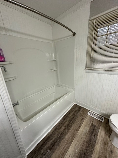 bathroom with shower / bathtub combination, wood-type flooring, and toilet