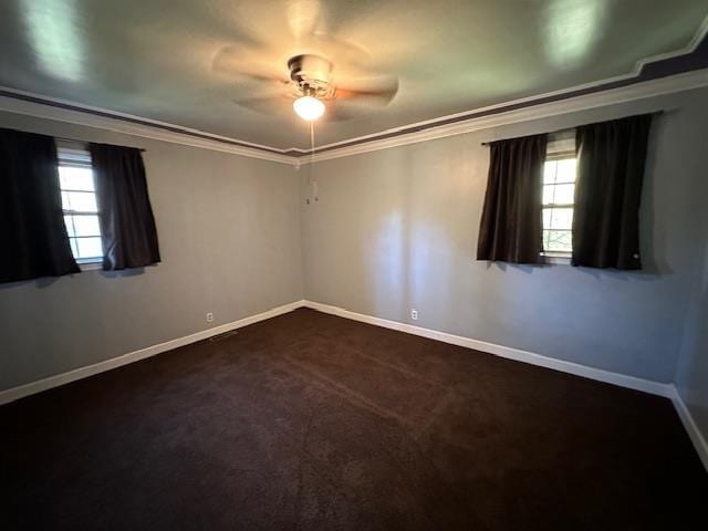 spare room with dark colored carpet, ornamental molding, and ceiling fan