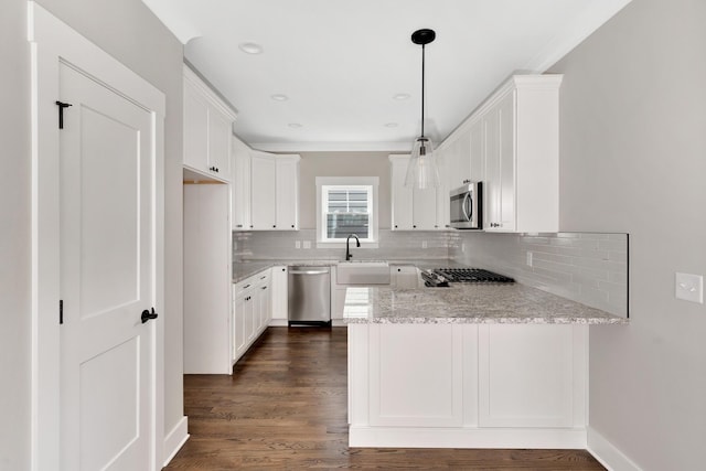 kitchen with light stone counters, stainless steel appliances, decorative light fixtures, and white cabinets