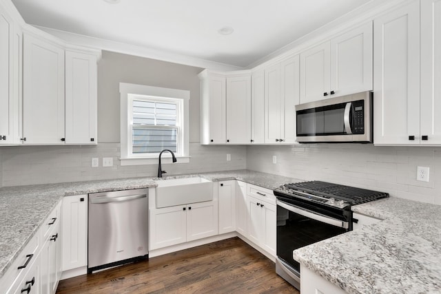 kitchen with stainless steel appliances, white cabinetry, sink, and light stone counters