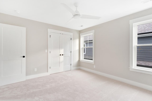 unfurnished bedroom featuring ceiling fan, a closet, and light carpet