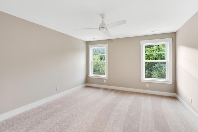 empty room with ceiling fan, a healthy amount of sunlight, and light carpet