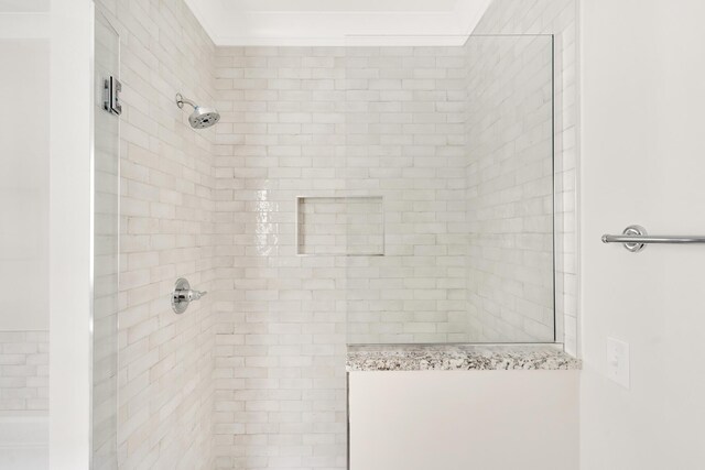 bathroom featuring a tile shower and crown molding