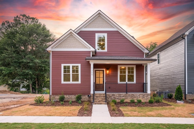 view of front of house featuring covered porch, a yard, and central AC unit