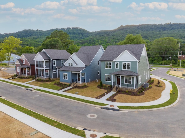 view of front of property featuring roof with shingles, central AC, a mountain view, a residential view, and a forest view