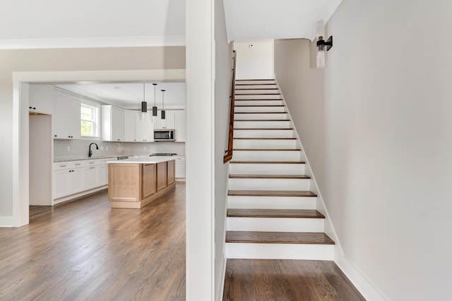 staircase with ornamental molding, baseboards, and wood finished floors