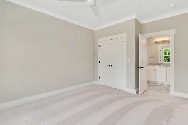 unfurnished bedroom with light carpet, baseboards, a ceiling fan, ensuite bath, and crown molding