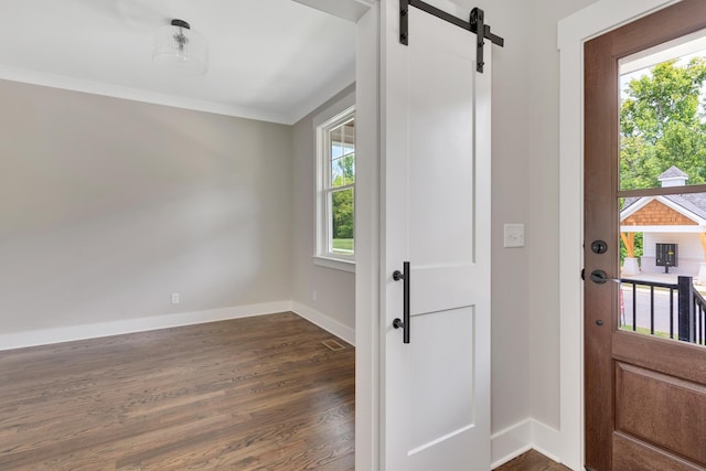 entryway with crown molding, dark wood finished floors, baseboards, and a barn door