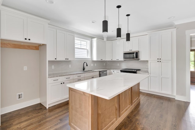 kitchen with light stone counters, a kitchen island, white cabinets, appliances with stainless steel finishes, and pendant lighting