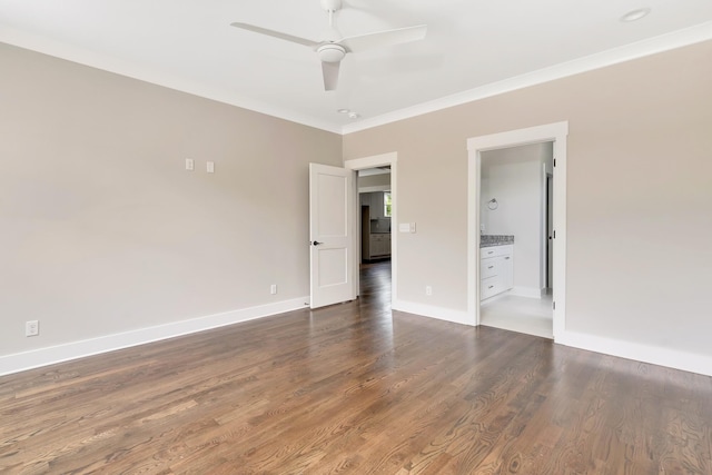 unfurnished bedroom featuring ceiling fan, dark wood-type flooring, baseboards, ornamental molding, and ensuite bath