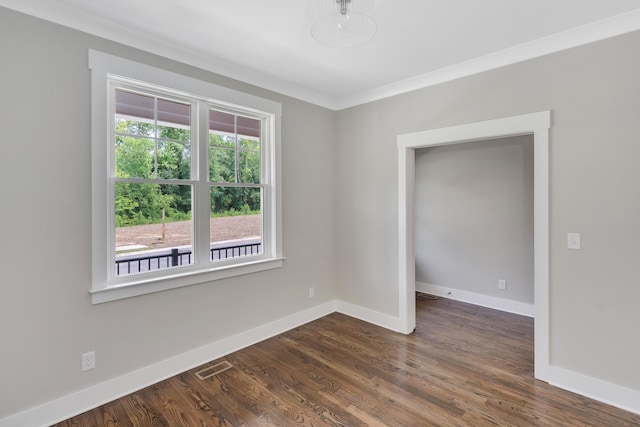 spare room with baseboards, crown molding, visible vents, and dark wood-type flooring