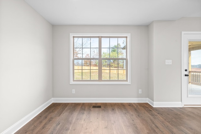 empty room with dark hardwood / wood-style floors and plenty of natural light