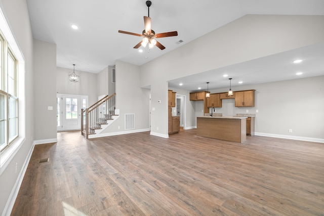 unfurnished living room featuring dark hardwood / wood-style floors, ceiling fan with notable chandelier, and high vaulted ceiling